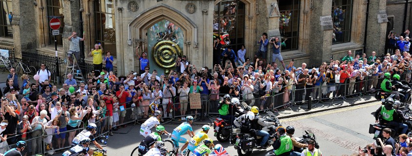 The 2014 Tour de France riding past the Chronophage clock at Corpus Christi College Cambridge